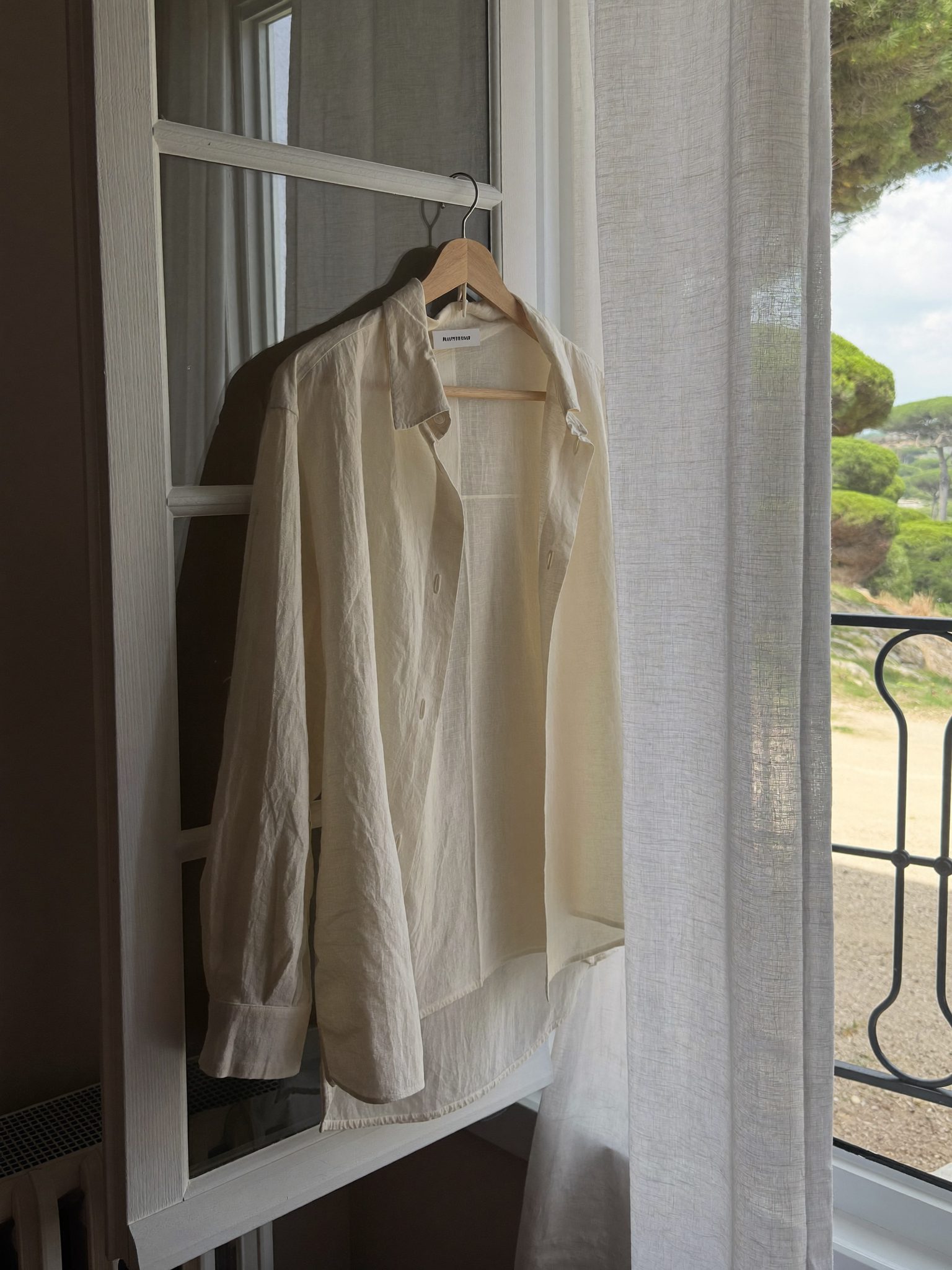 Peça de roupa pendurada num cabide de madeira a arejar